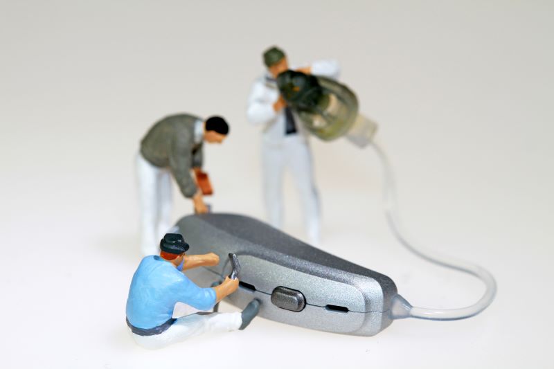 hearing aid repair simulated with three minute hearing aid technician figurines
