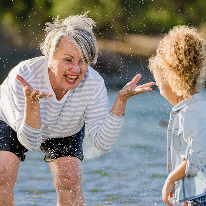 grandmother playing in water with their grandchild while wearing Beltone hearing aids