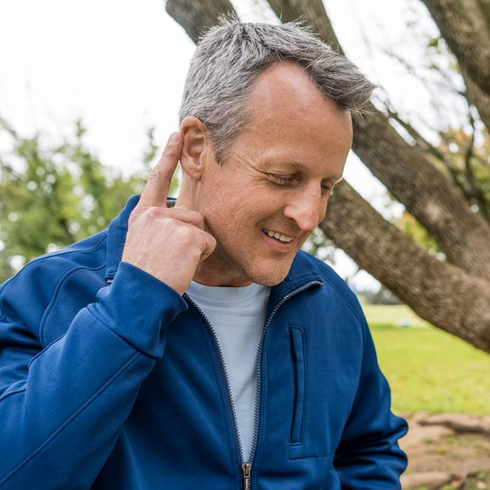 a Beltone hearing aid wearer tapping their hearing aid to take a phone call